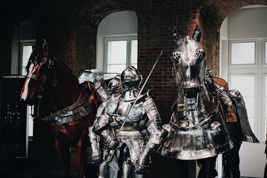 Medieval knight in full armor with a swordsman and armored horse indoors.